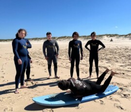 Uczniowie ćwiczą surfing w płytkiej wodzie Atlantyku.