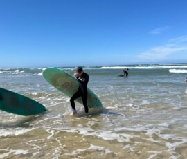 Uczniowie w piankach surfingowych przygotowują się do kolejnego wejścia do wody.