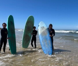 Uczniowie i opiekunowie podsumowują zajęcia surfingowe na plaży.