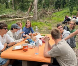 Grupa uczestników Erasmus+ je wspólny posiłek na świeżym powietrzu.