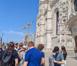 Grupa uczniów stoi przy charakterystycznym pomniku podczas wycieczki.
