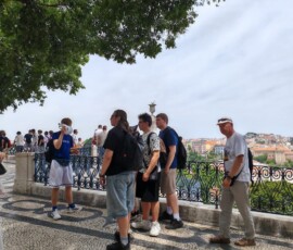 Grupa uczniów pozuje na tle zabudowy Lizbony.