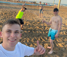 Uczeń robi zdjęcie na plaży w Walencji, a w tle widać innych uczestników wyjazdu.