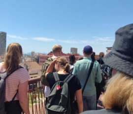 Uczestnicy wycieczki stoją przy balustradzie na tarasie widokowym nad Alicante.