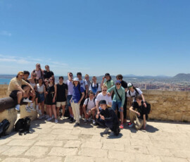 Grupa uczestników Erasmus+ pozuje przy armacie z panoramą Alicante w tle.