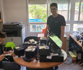 Dwóch uczestników pracuje przy komputerach i sprzęcie elektronicznym podczas praktyk w hiszpańskiej firmie.