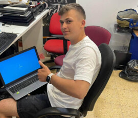 Uczeń pracuje przy laptopie na stanowisku serwisowym podczas zagranicznych praktyk zawodowych.