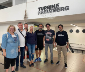 Nauczyciele i uczniowie pozują przy szyldzie Turbine Nürnberg podczas wizyty związanej z mobilnością.