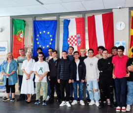 Nauczyciele i uczestnicy z różnych krajów pozują na tle flag podczas mobilności job shadowing w Walencji.