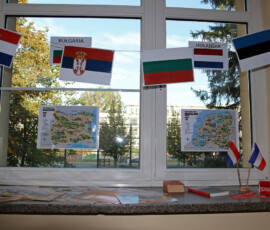Szkolna dekoracja z flagami kilku państw i materiałami ułożonymi na parapecie.