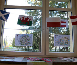 Flagi różnych państw i mapy umieszczone na oknie w ramach szkolnej wystawy językowej.