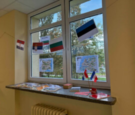 Dekoracja szkolnego okna z flagami i materiałami poświęconymi różnym państwom.