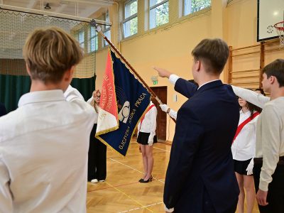 Uczniowie stoją przy poczcie sztandarowym podczas uroczystego rozpoczęcia roku szkolnego.