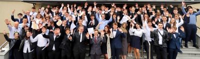 Duża grupa uczniów i pracowników ZSŁ pozuje wspólnie, unosząc ręce do zdjęcia.