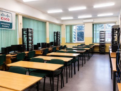 Pracownia sieci komputerowych ZSŁ z rzędami stanowisk komputerowych Cisco Networking Academy.