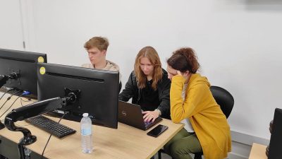 Uczniowie ZSŁ rozmawiają przy stanowisku komputerowym podczas praktyk zawodowych w Portugalii.